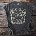 Dark gray t-shirt with cream illustration of a mothman in a forest setting.