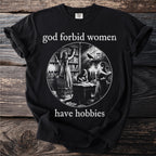 Black t-shirt with text "god forbid women have hobbies" and circular illustration.