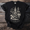 Black t-shirt with botanical illustration of "The Poison Garden" featuring toxic plants.