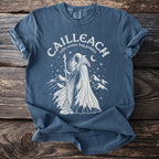 Celtic Cailleach winter hag goddess with crow and mountains on blue t-shirt.
