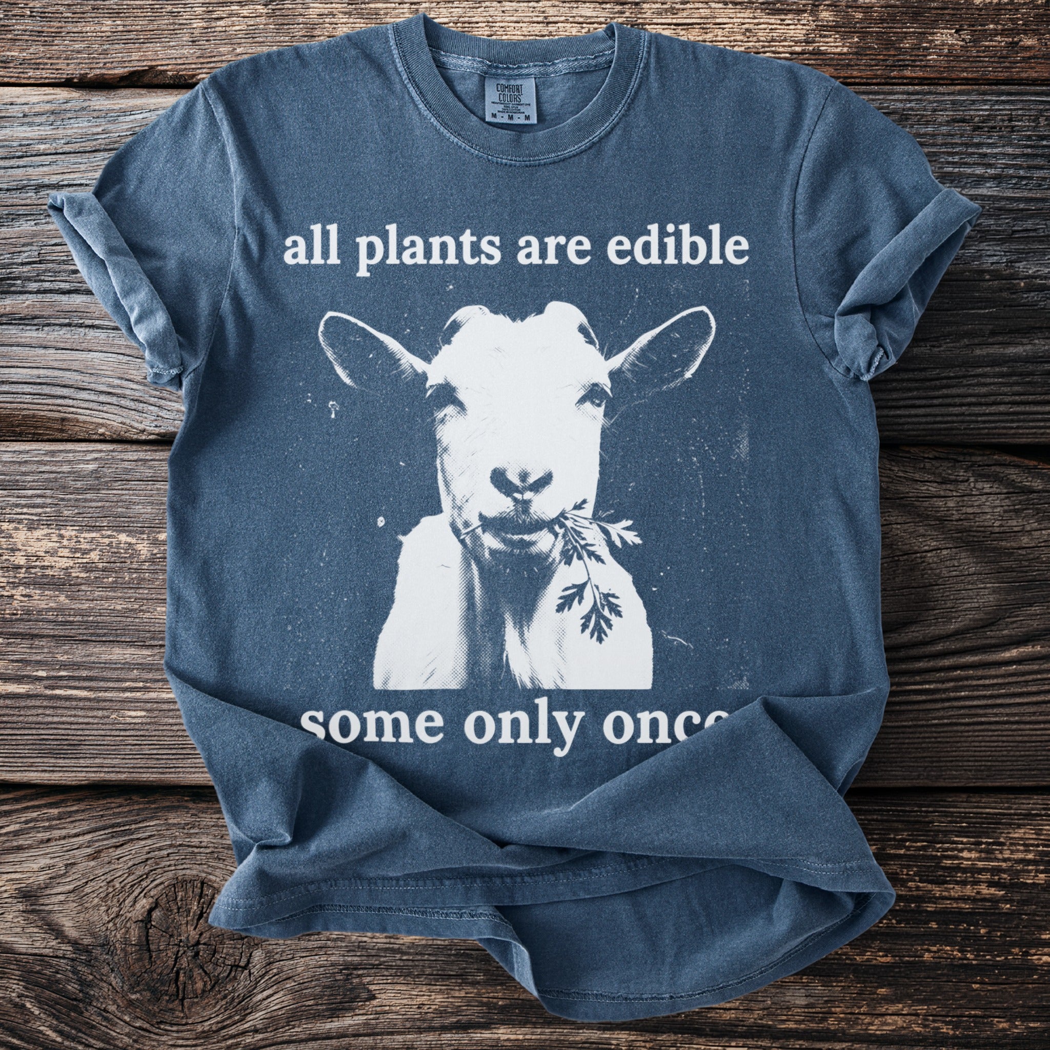 T-shirt with white goat eating greens and text "all plants are edible some only once".