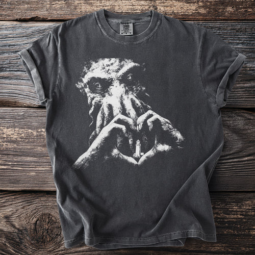 Dark t-shirt with white graphic of Cthulhu's face and hands forming heart around a lighthouse.