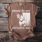 Brown t-shirt with a cat peeking from behind a curtain and the text "please do not perceive me".