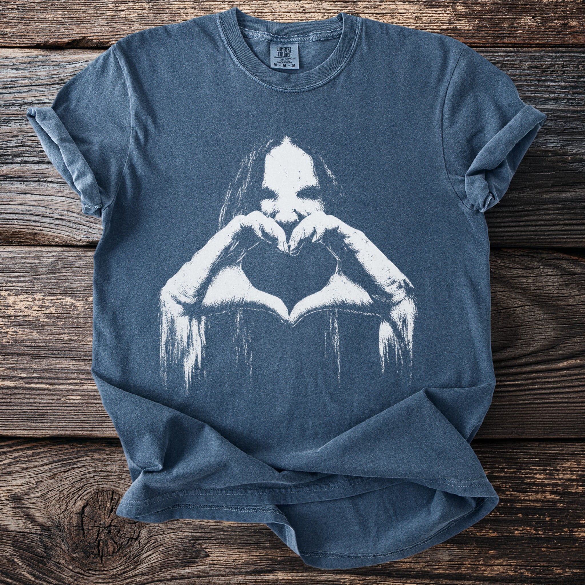 Blue t-shirt with white graphic of a face and hands forming a heart