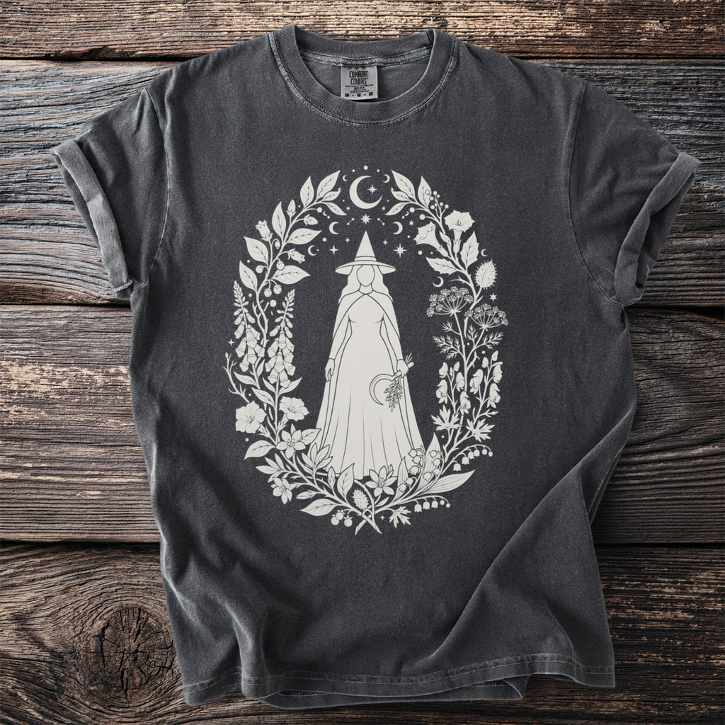 Dark gray t-shirt with white oval design of a witch illustration in floral wreath.
