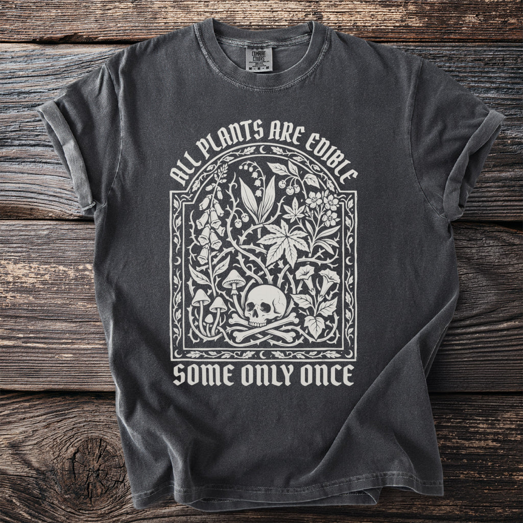 Dark t-shirt with "ALL PLANTS ARE EDIBLE SOME ONLY ONCE" and botanical skull design.