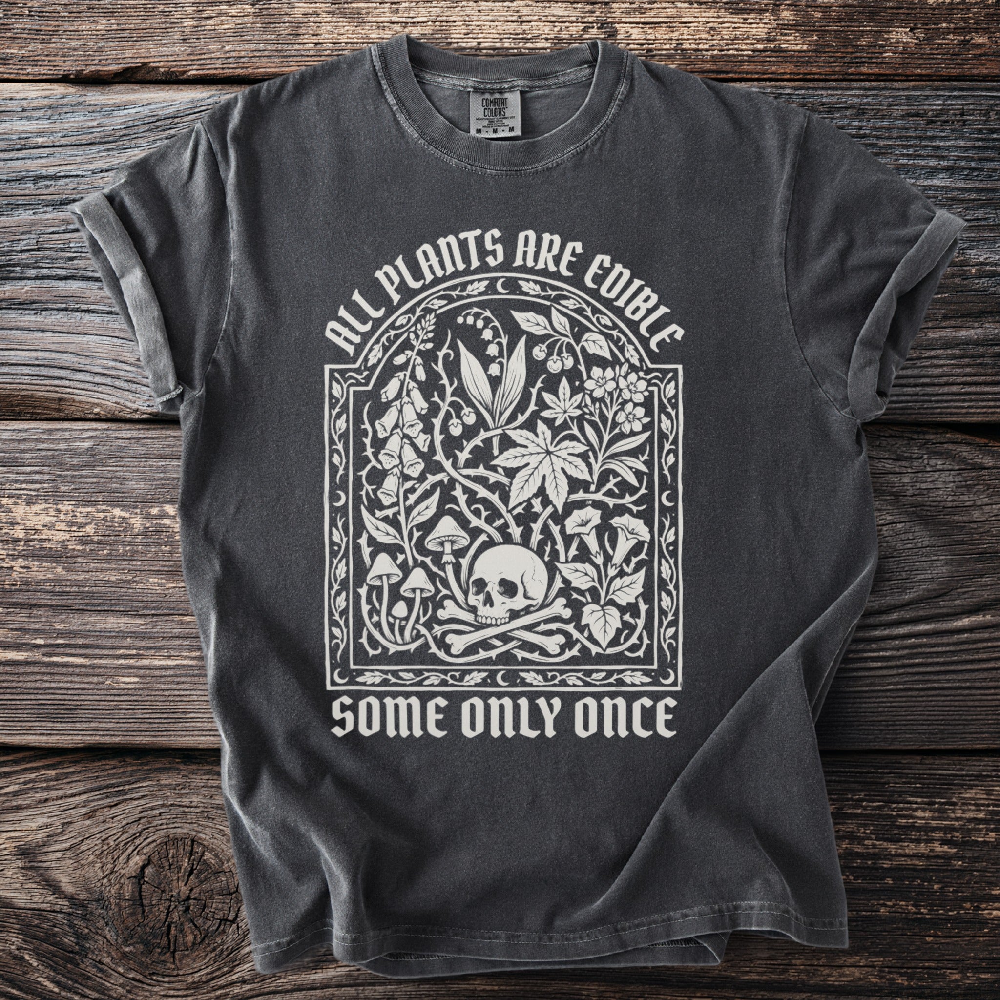 Dark t-shirt with "ALL PLANTS ARE EDIBLE SOME ONLY ONCE" and botanical skull design.