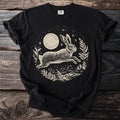Black t-shirt with a cream linocut style design of a running rabbit beneath a moon and stars.