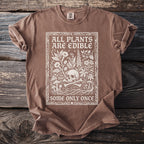 Brown t-shirt with white graphic of a skull, bones, plants, and text.