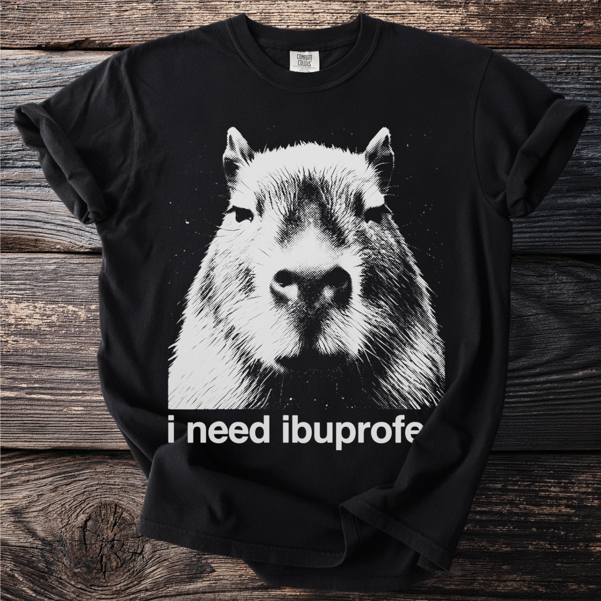 Black t-shirt with a close-up black and white graphic of a capybara face and text that reads "i need ibuprofe".