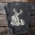 Dark grey t-shirt with a cream graphic of a horned, leafy figure interacting with a cat.