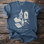 Blue t-shirt with a detailed line drawing of a naturalist's table and text.