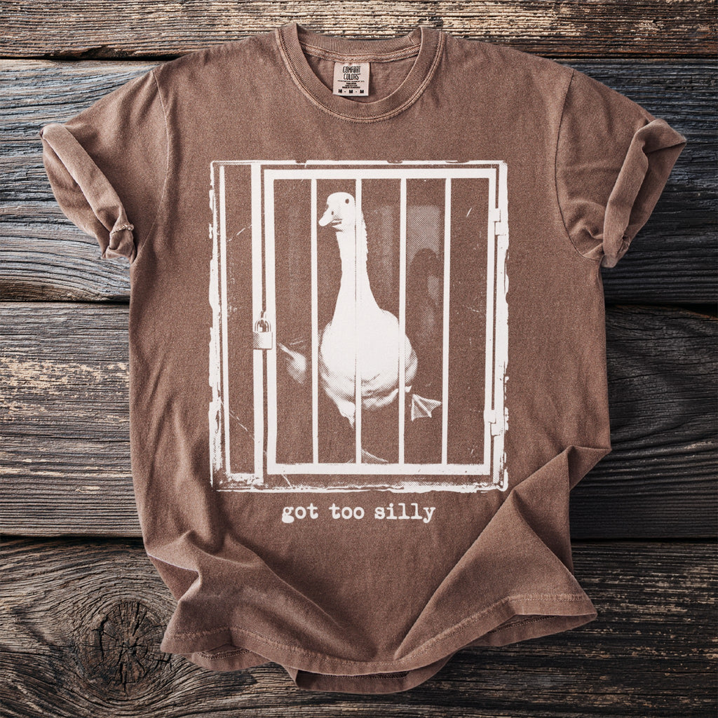 Brown t-shirt with a white graphic of a goose in a cage and text: "got too silly."