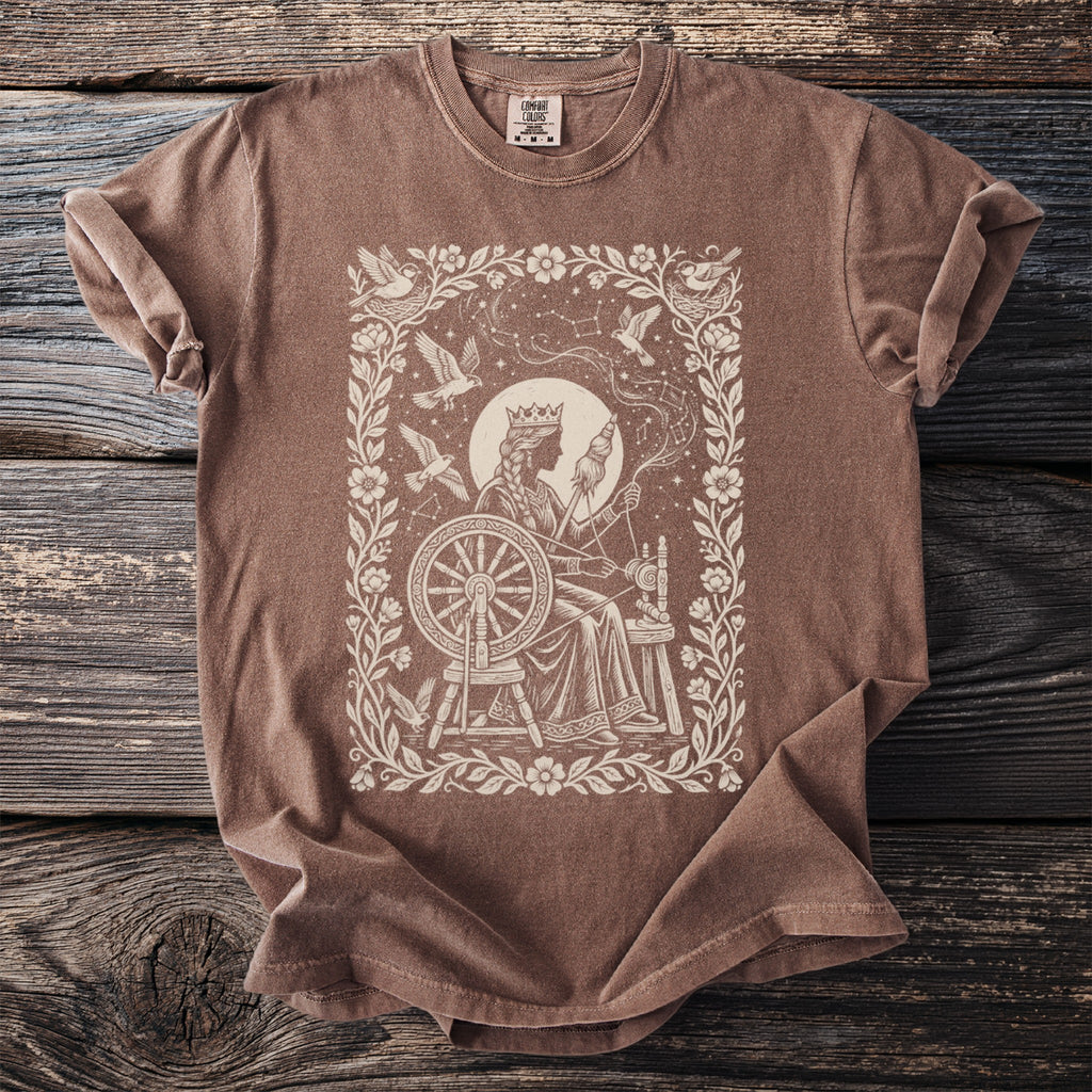 Brown t-shirt with a cream-colored graphic of a queen at a spinning wheel.