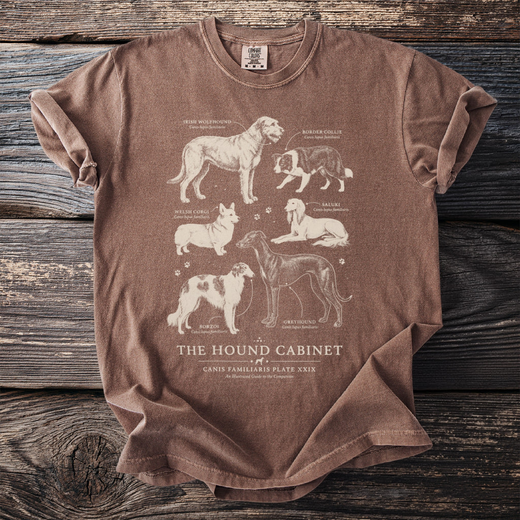 Brown t-shirt with illustrated dog breeds: Irish Wolfhound, Border Collie, Welsh Corgi, Saluki, Borzoi, and Greyhound.