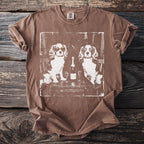 Brown t-shirt with a white graphic of two dogs, champagne, and glasses.