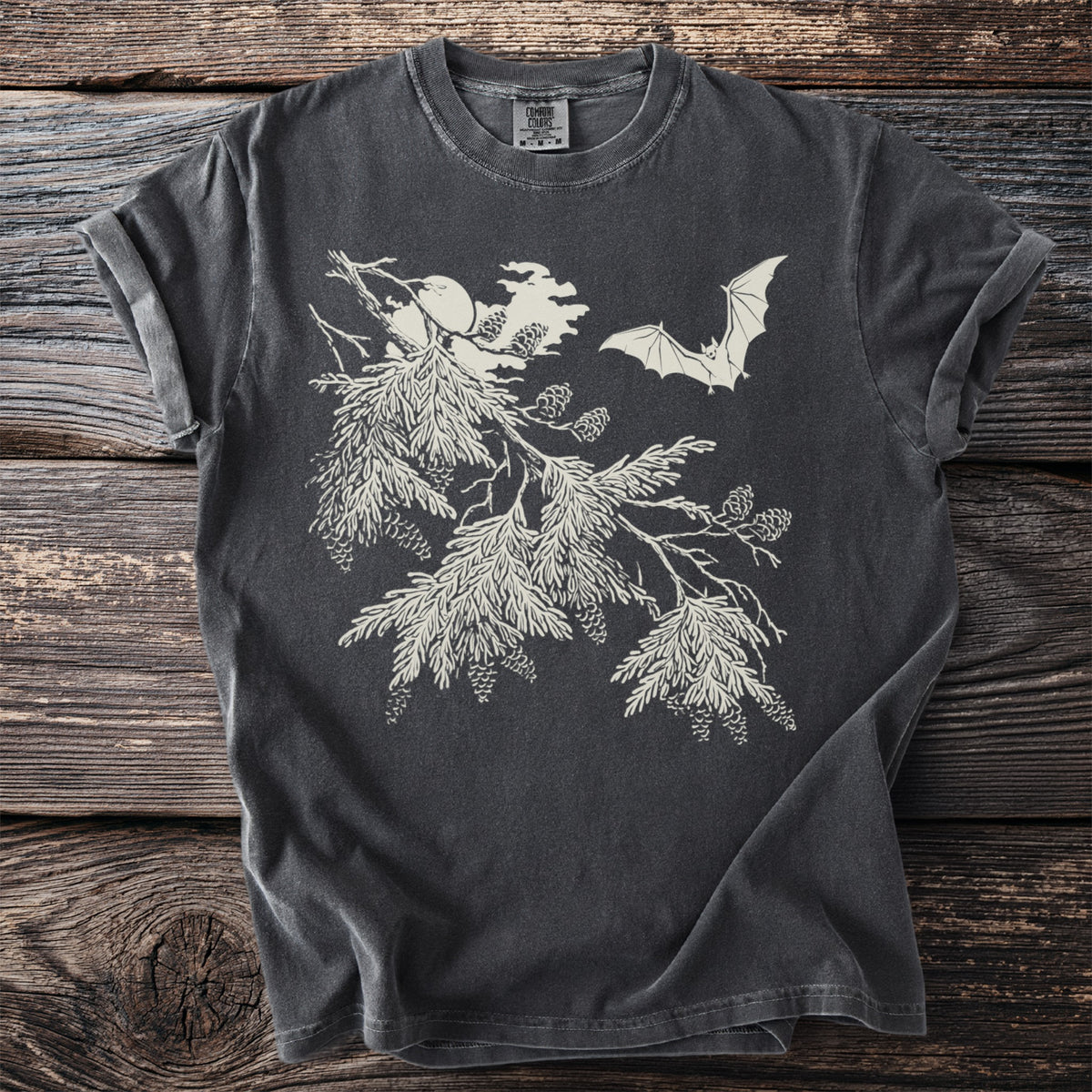 Dark grey t-shirt with white illustration of pine branches, pinecones, and a bat.
