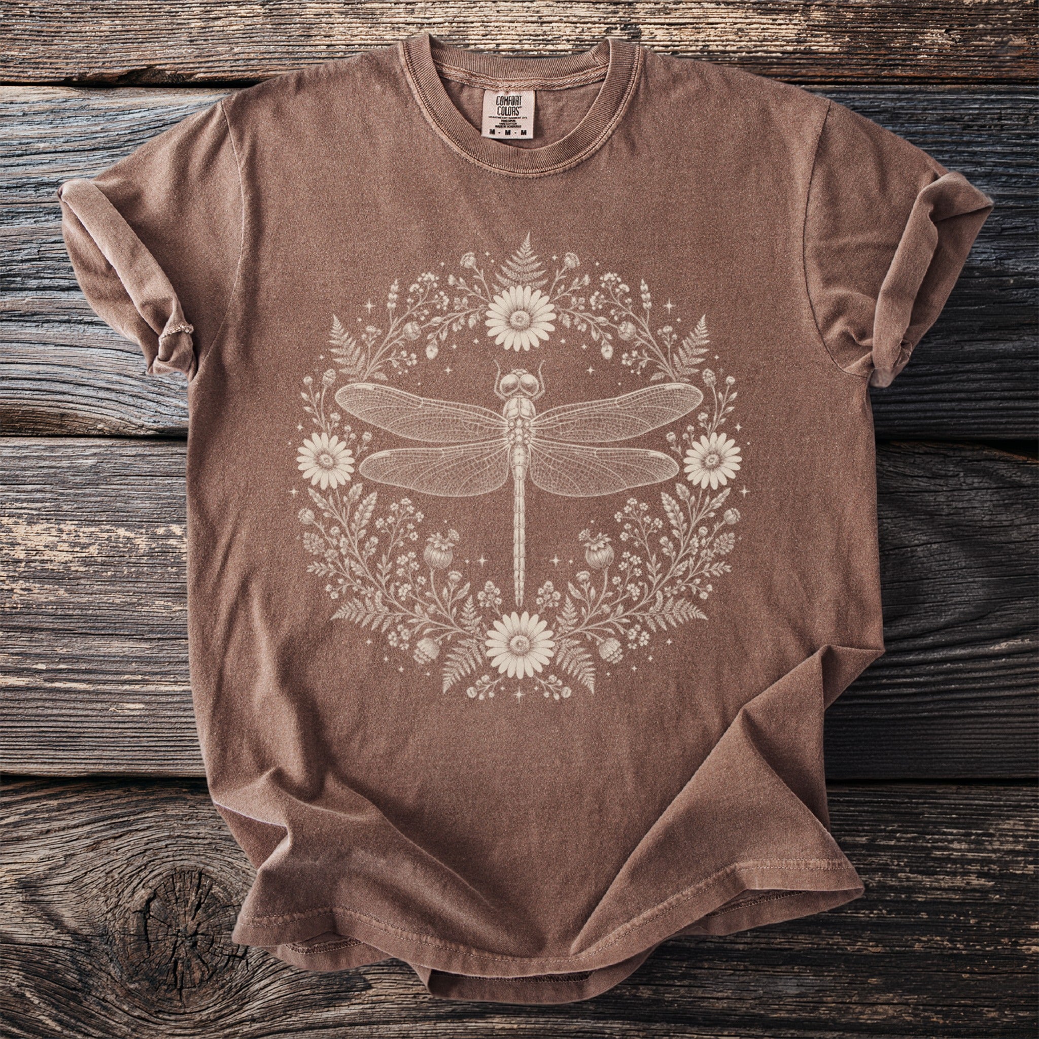 Brown t-shirt with a cream-colored dragonfly and floral design in a circular frame.