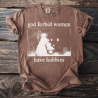 Brown t-shirt with white text "god forbid women have hobbies" and a vintage image.