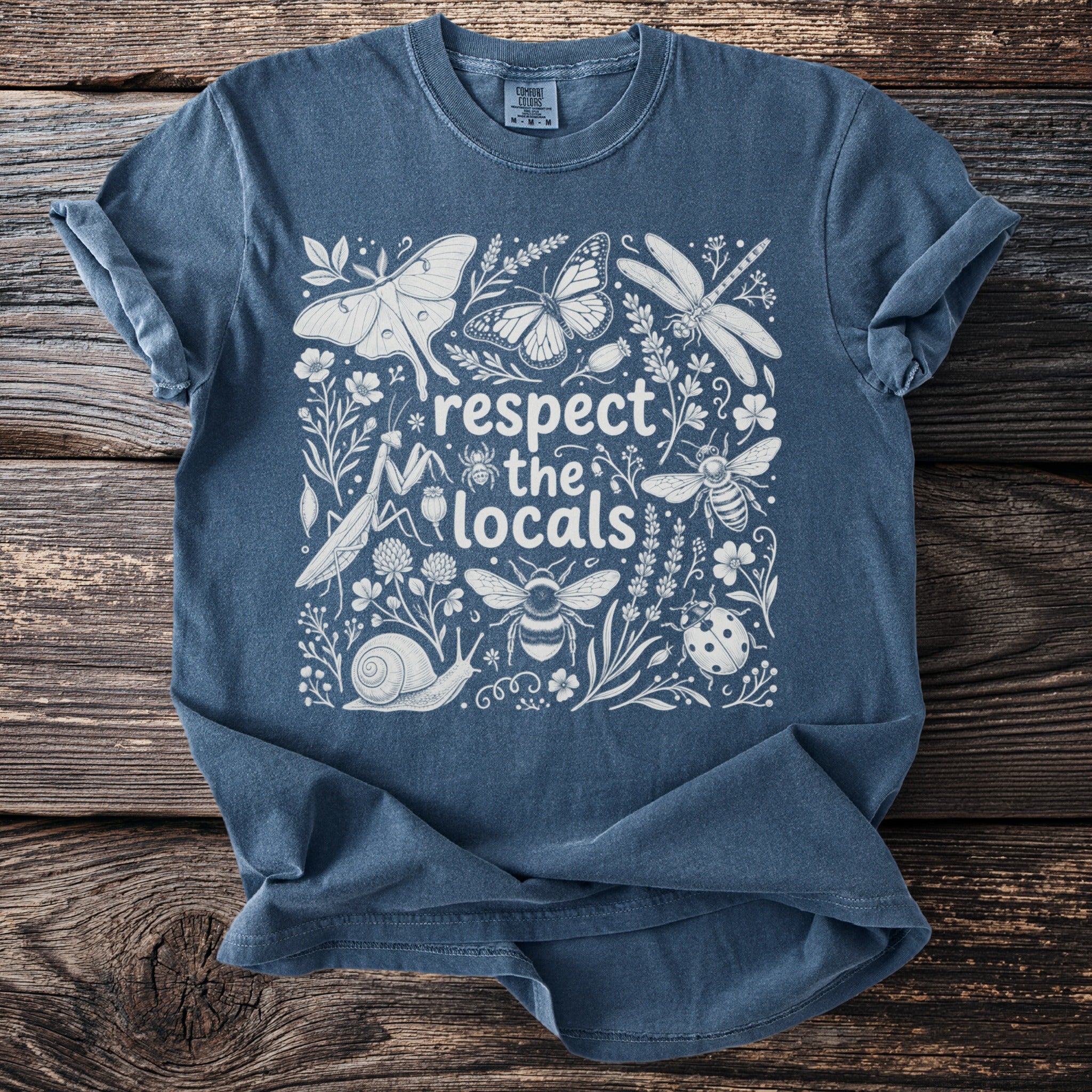 Blue t-shirt with white illustration of insects, flowers, and the text "respect the locals."