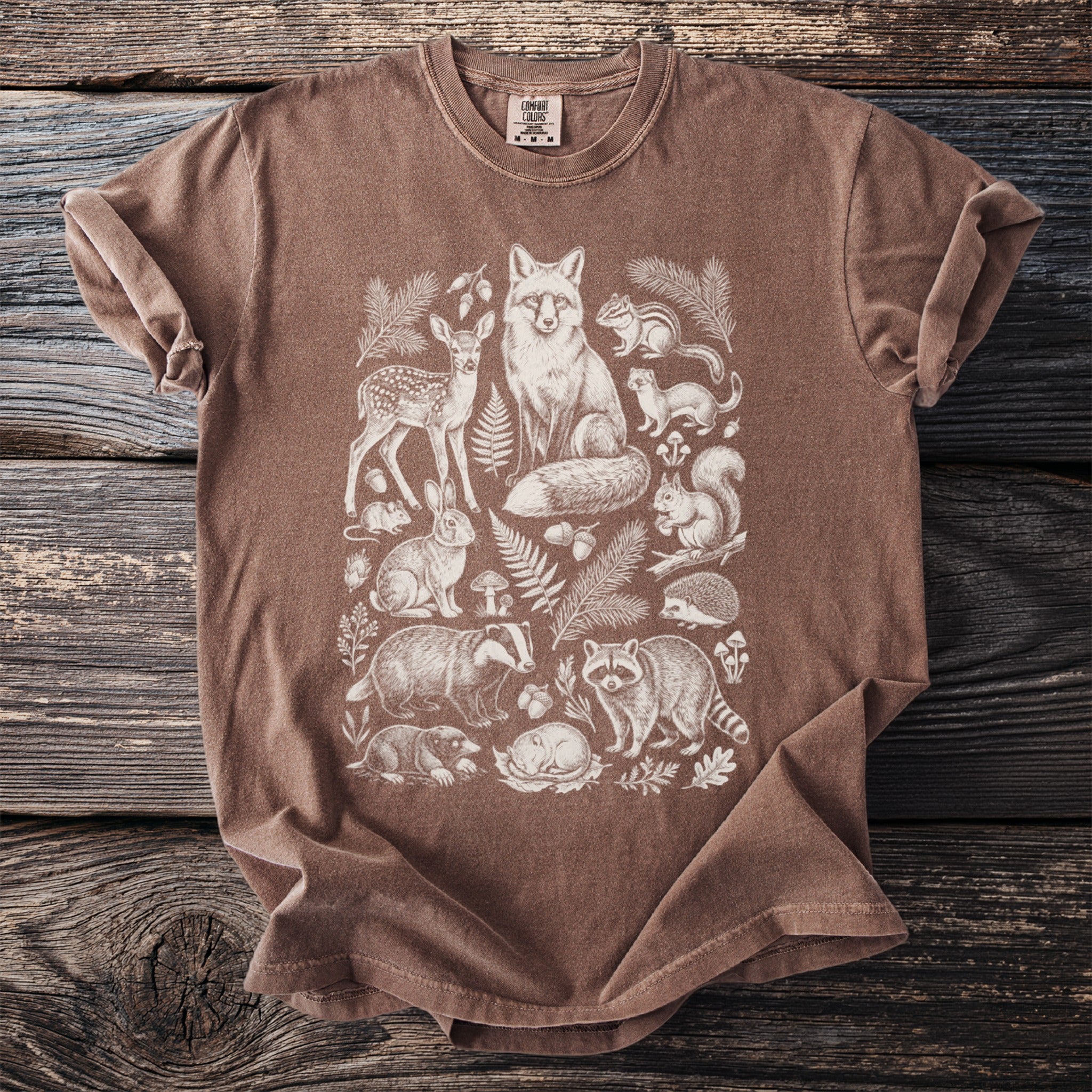 Brown t-shirt with a white line drawing of woodland animals and foliage.