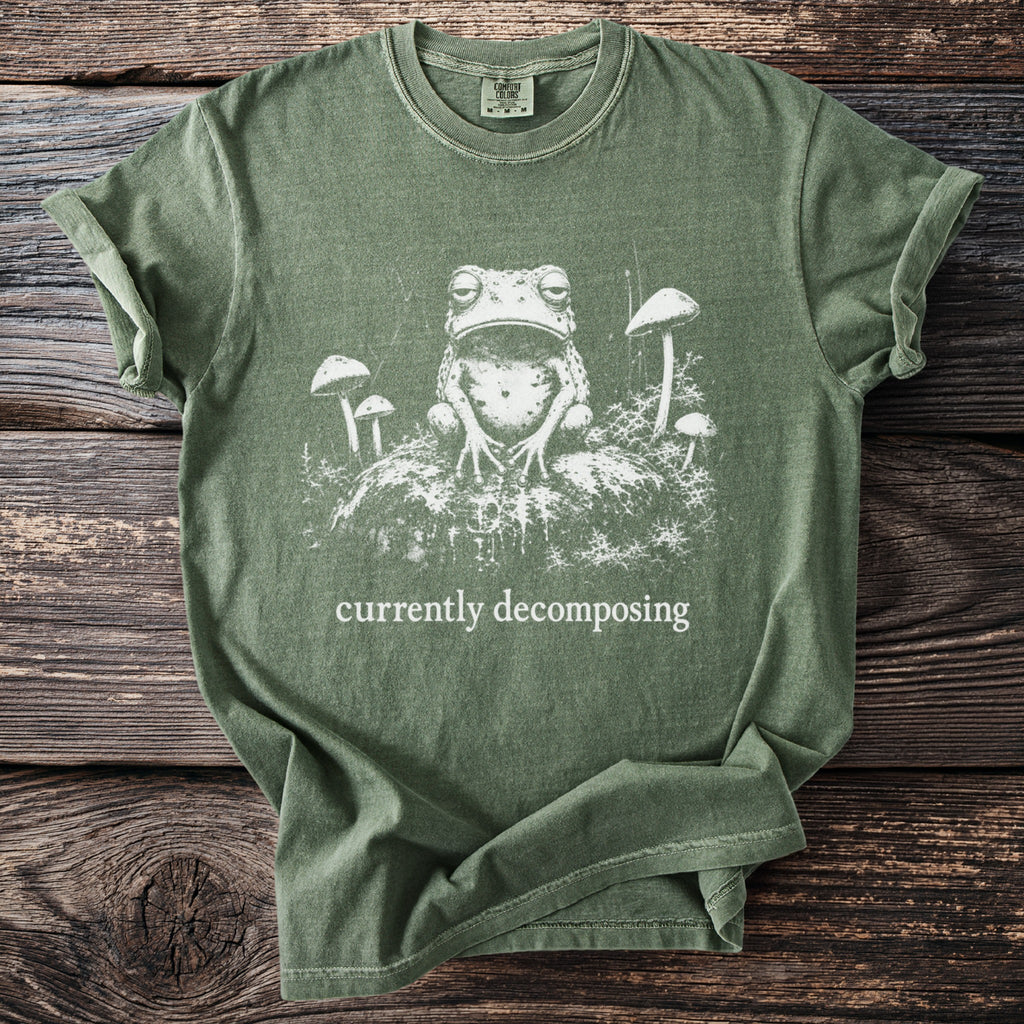 Green t-shirt with a distressed print of a frog and mushrooms, reads "currently decomposing".