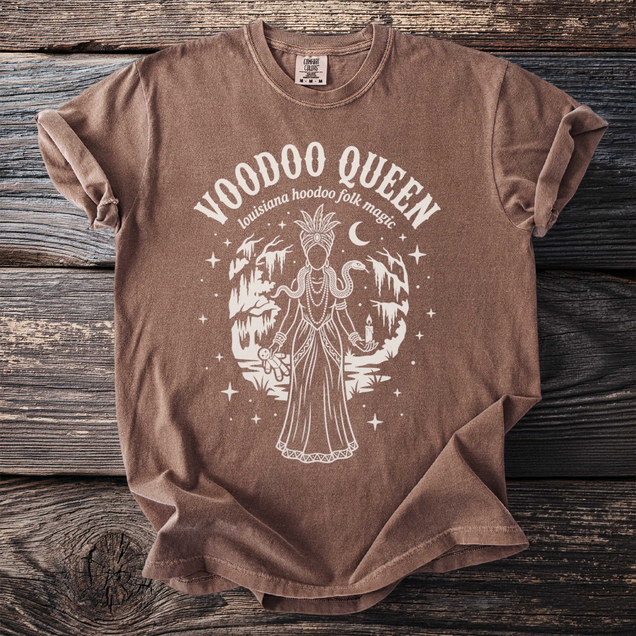 Brown t-shirt with Voodoo Queen graphic featuring a draped figure, snake, candle, and voodoo doll.