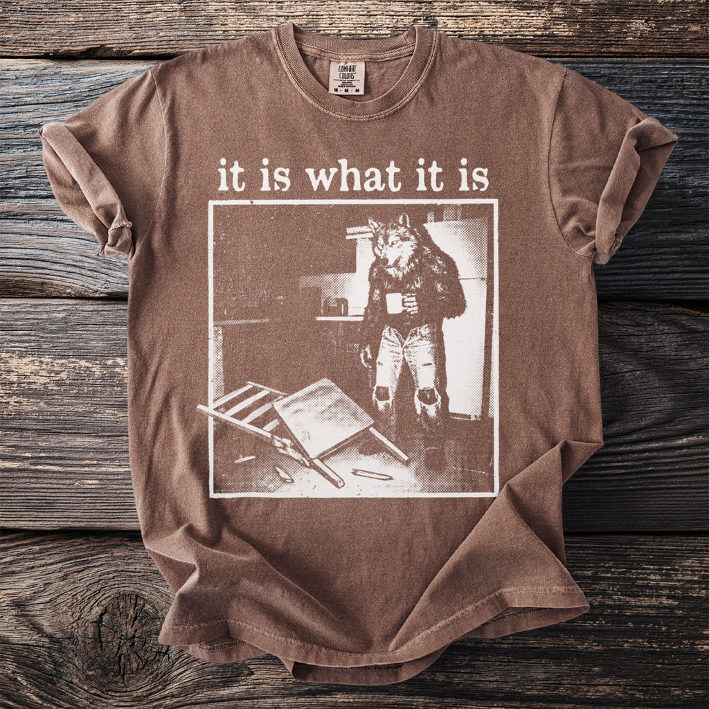 Brown t-shirt with "it is what it is" text and a werewolf character holding coffee.