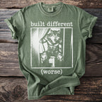 Green t-shirt with a graphic of a wolf in clothes and text "built different (worse)".