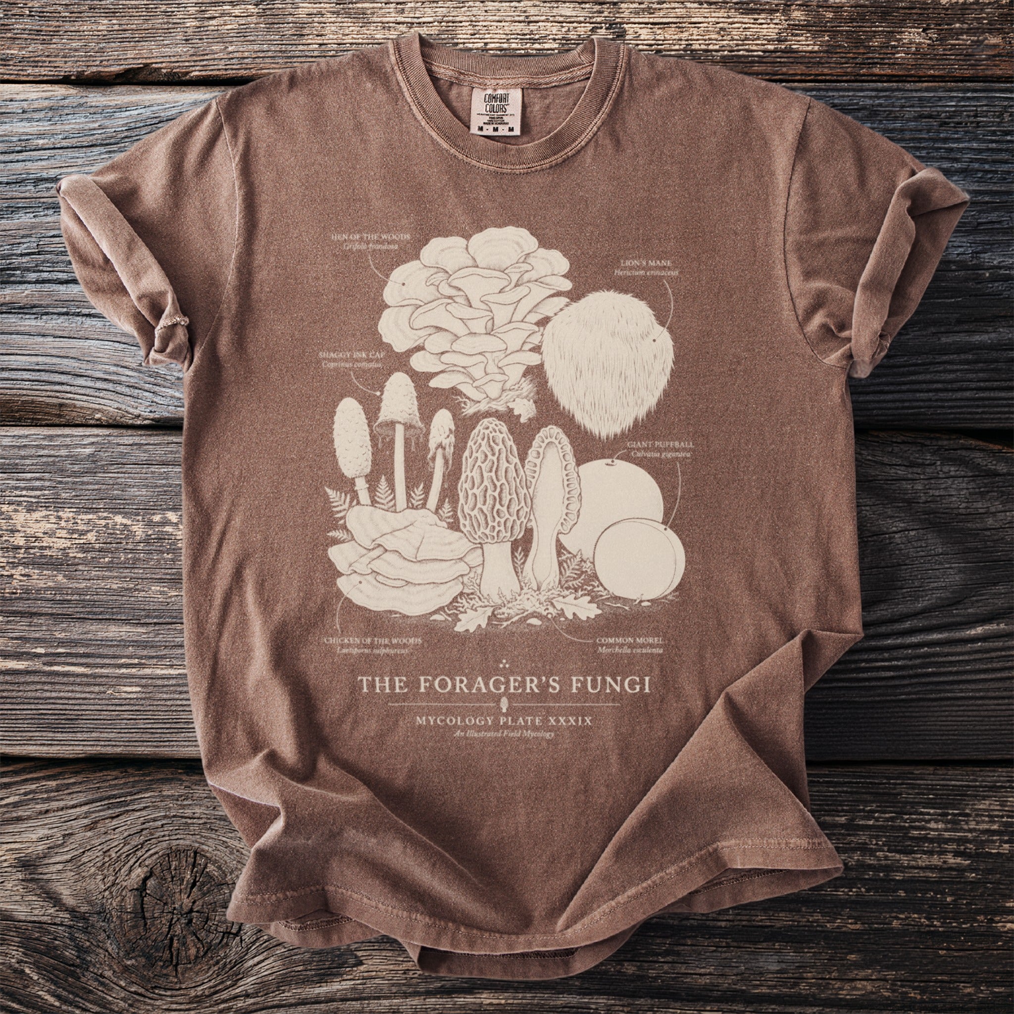 Brown t-shirt featuring a cream line drawing of various fungi labeled "The Forager's Fungi".