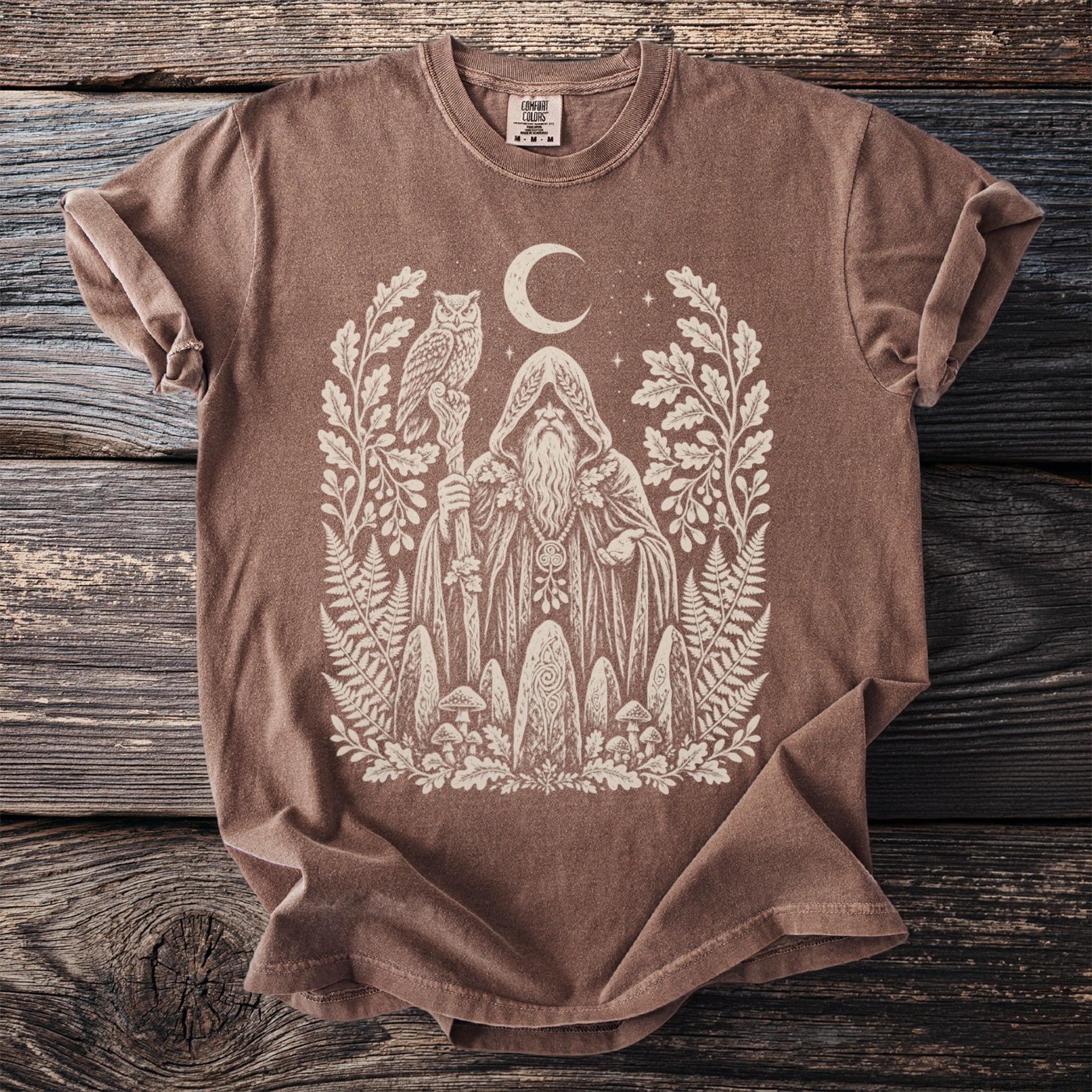 Brown t-shirt with a white graphic of a wizard, owl, moon, and forest elements.