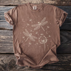 Brown t-shirt with white line art of dragonflies, dandelions, moons, and stars.