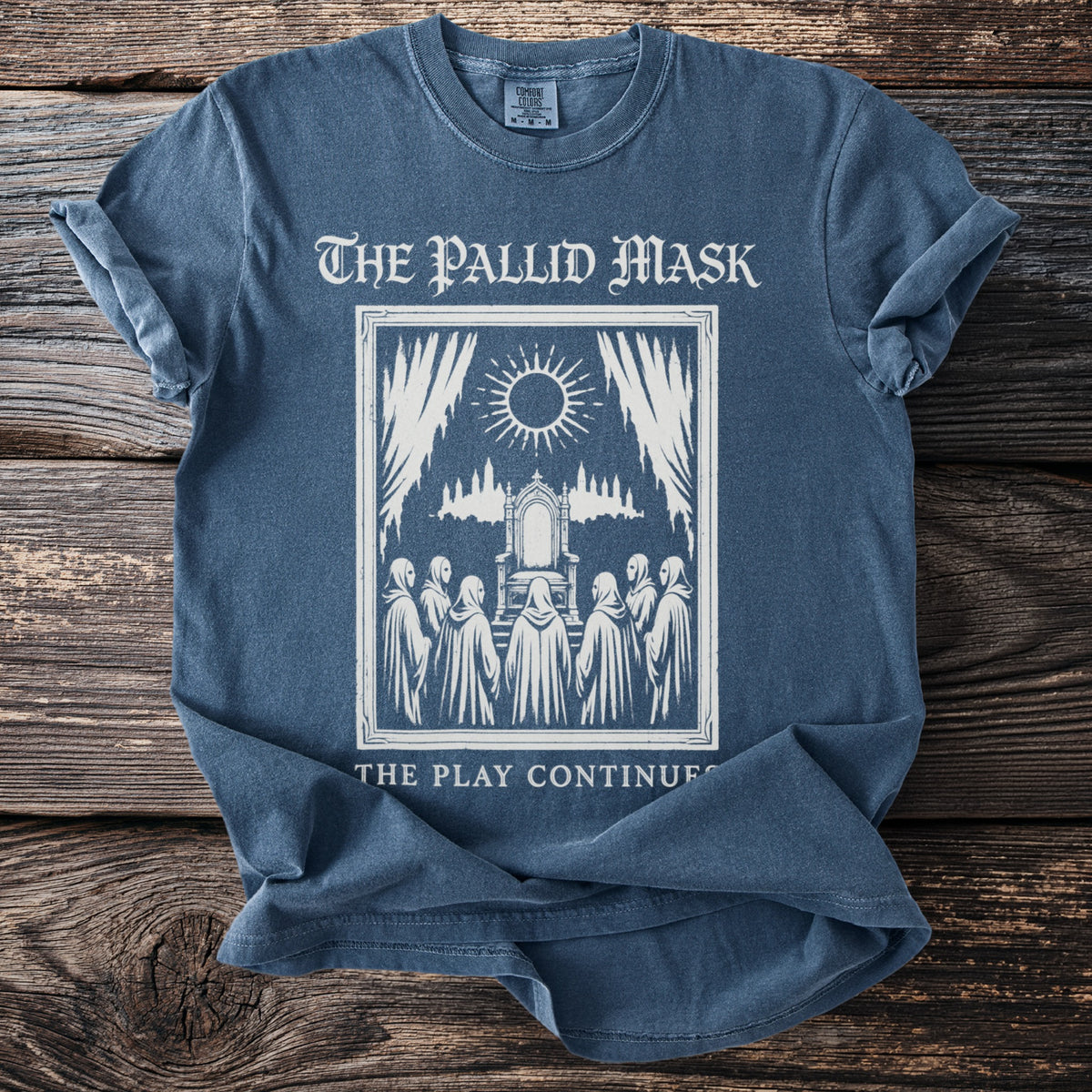 The Pallid Mask t-shirt graphic with robed figures facing a throne and the text "The Play Continues."