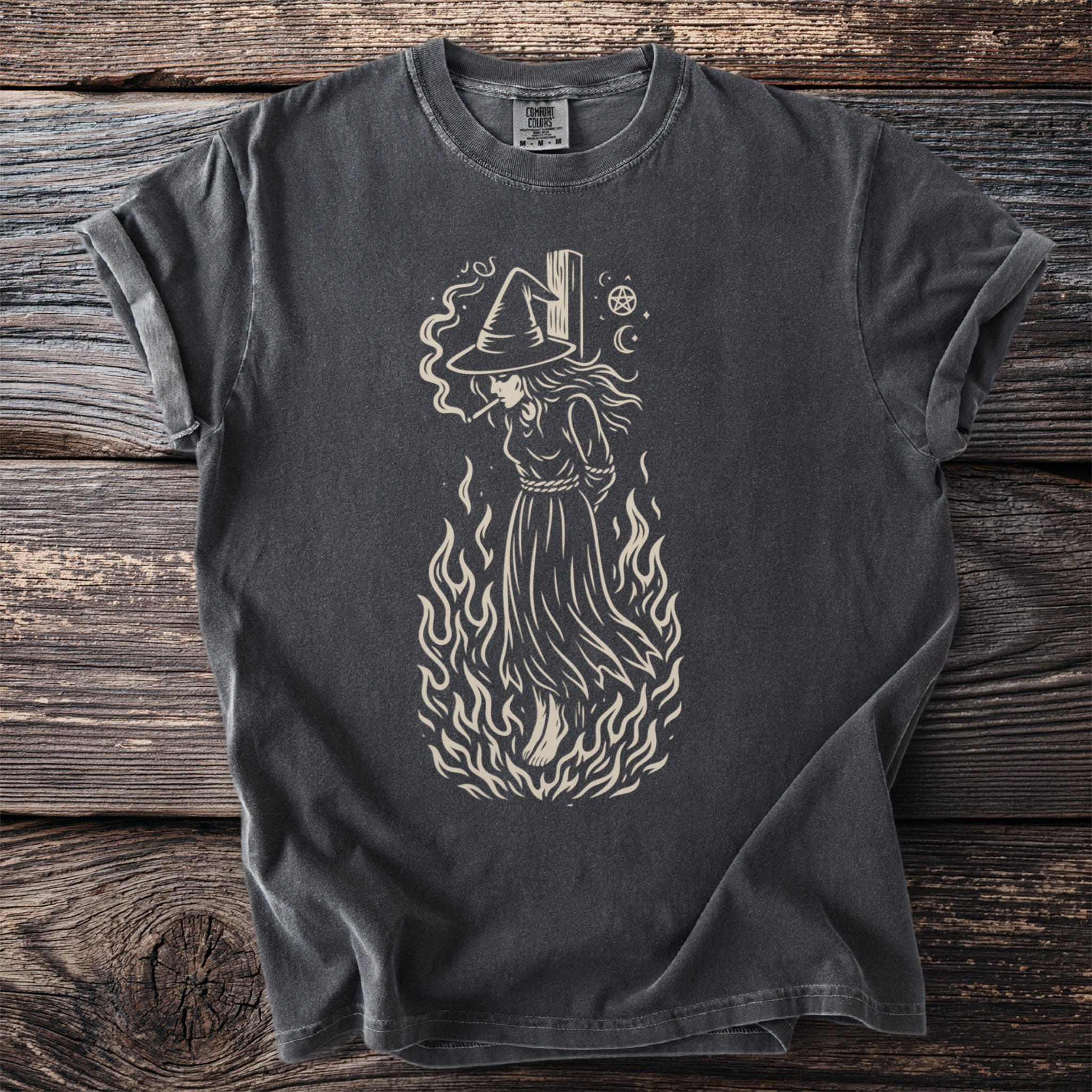 Dark grey t-shirt with illustration of a witch on a pyre with flames and a pentagram.