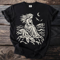 Black t-shirt with a beige graphic of a woman with flowing hair sitting by the sea.