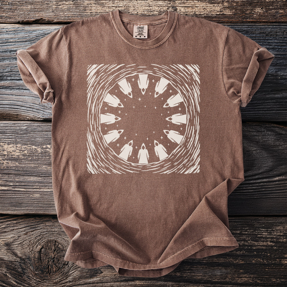 Brown t-shirt with a cream circular graphic of hooded figures and stars.
