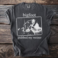 Dark grey t-shirt with white text "bigfoot grabbed my weiner" and a Bigfoot illustration.