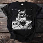 Raccoon wearing sunglasses drinking from a cup with a straw on a black t-shirt.
