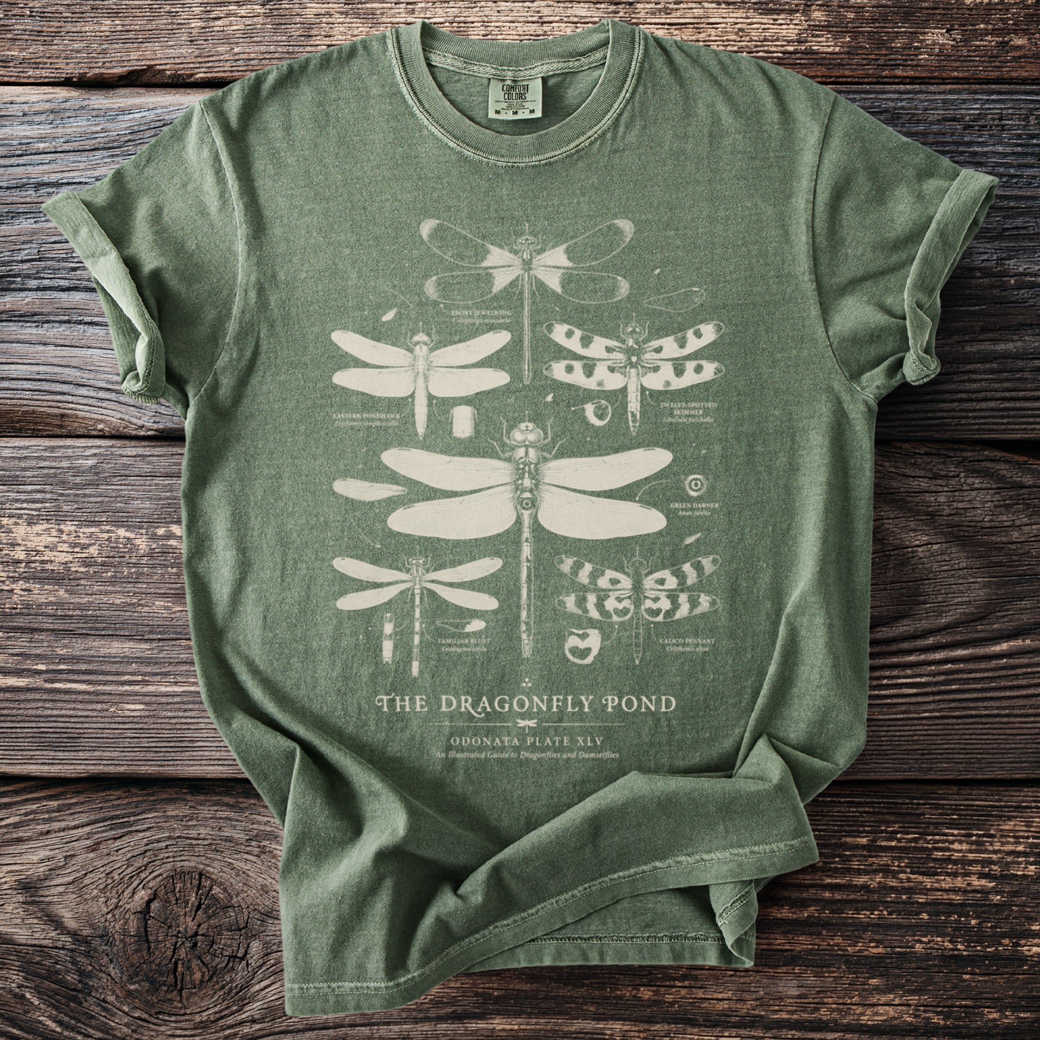 Green t-shirt with white illustration of dragonflies and text "The Dragonfly Pond".
