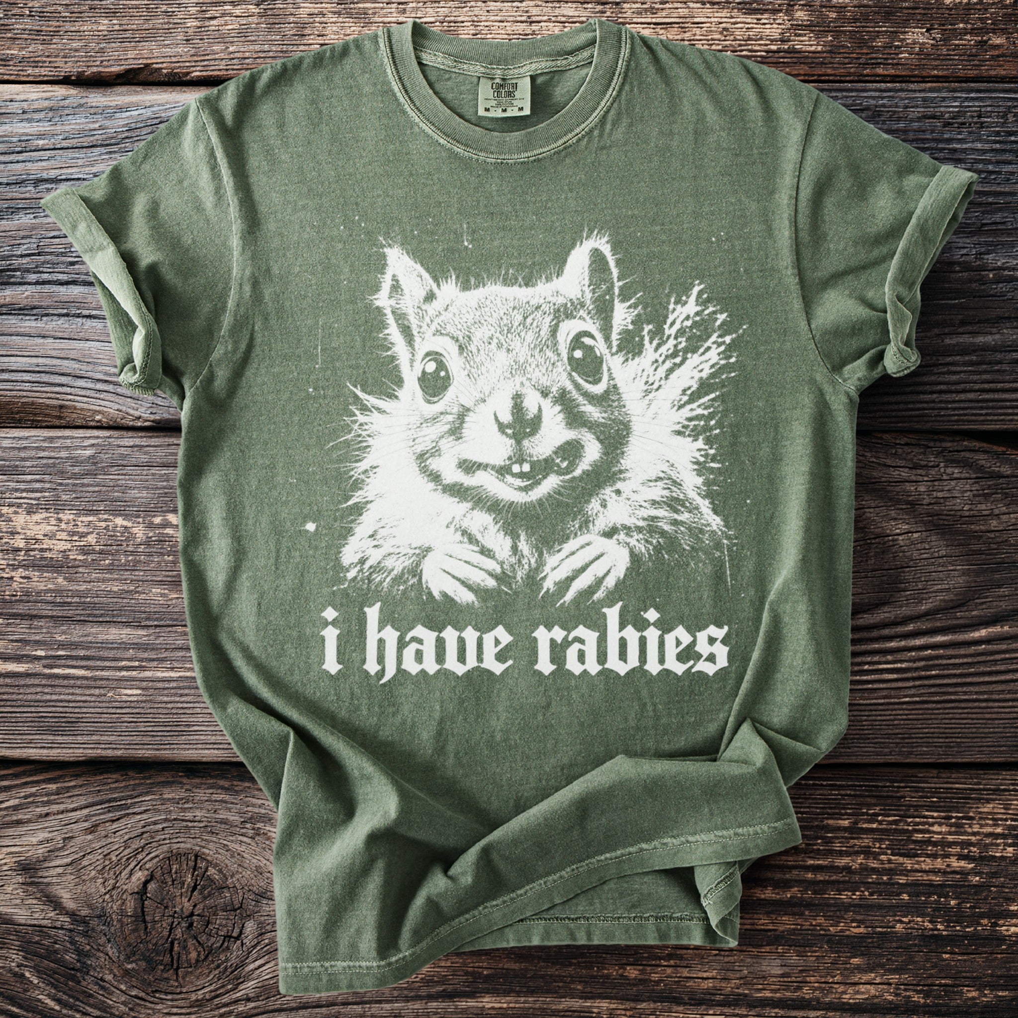 Olive green t-shirt with a white graphic of a squirrel and text reading "i have rabies".