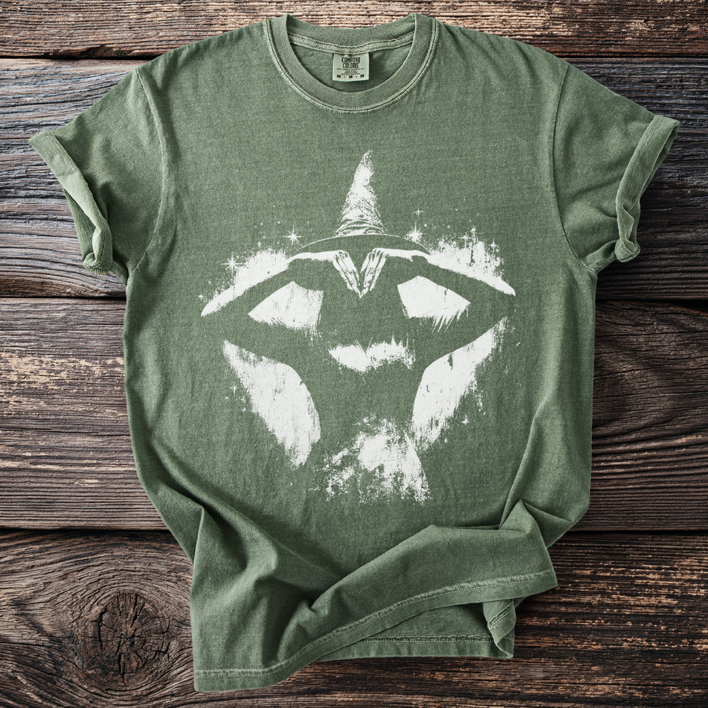Green t-shirt with a white witch silhouette and sparkling stars graphic.