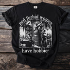 Black t-shirt with "god forbid women have hobbies" text and library illustration.