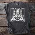 Dark grey t-shirt with white graphic of a horned figure making a heart shape with hands and a snake.