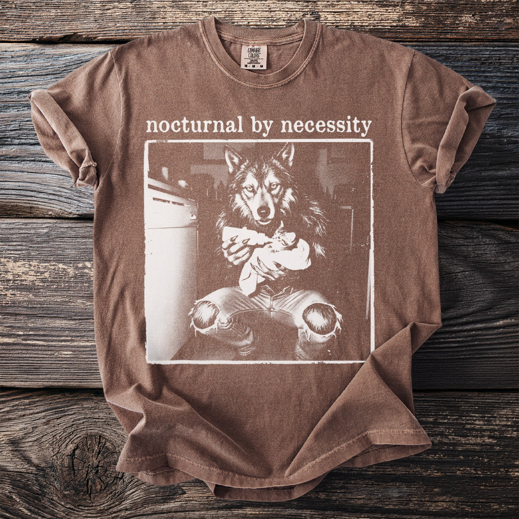 Brown t-shirt with wolf holding a baby and text "nocturnal by necessity."