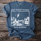 Blue t-shirt with "god forbid women have hobbies" text and an illustration.