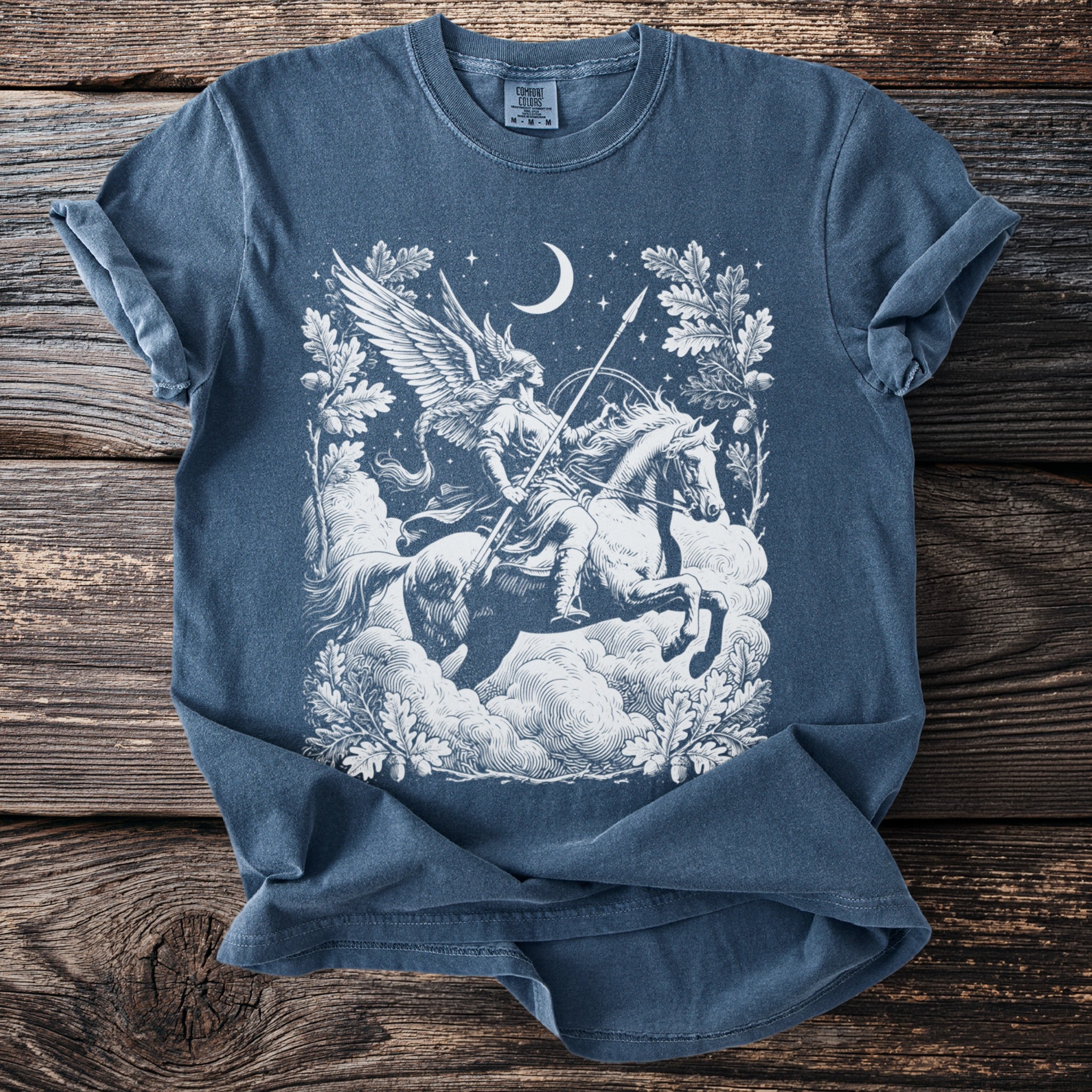 Blue t-shirt with white graphic of Valkyrie on horse under moon and stars.