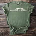 Olive green t-shirt with white crows and text reading "accessory to murder".