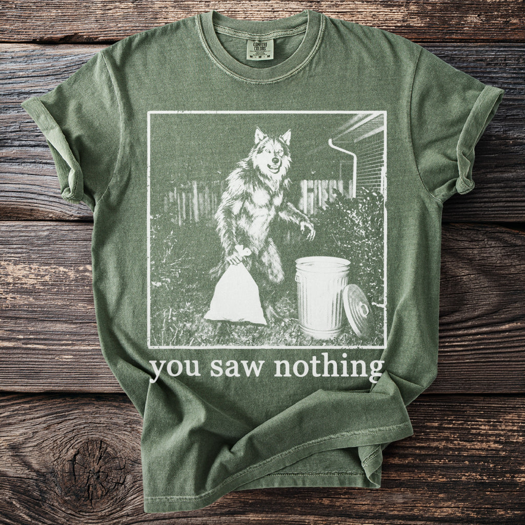 Green t-shirt with graphic of a werewolf taking out trash and text "you saw nothing."