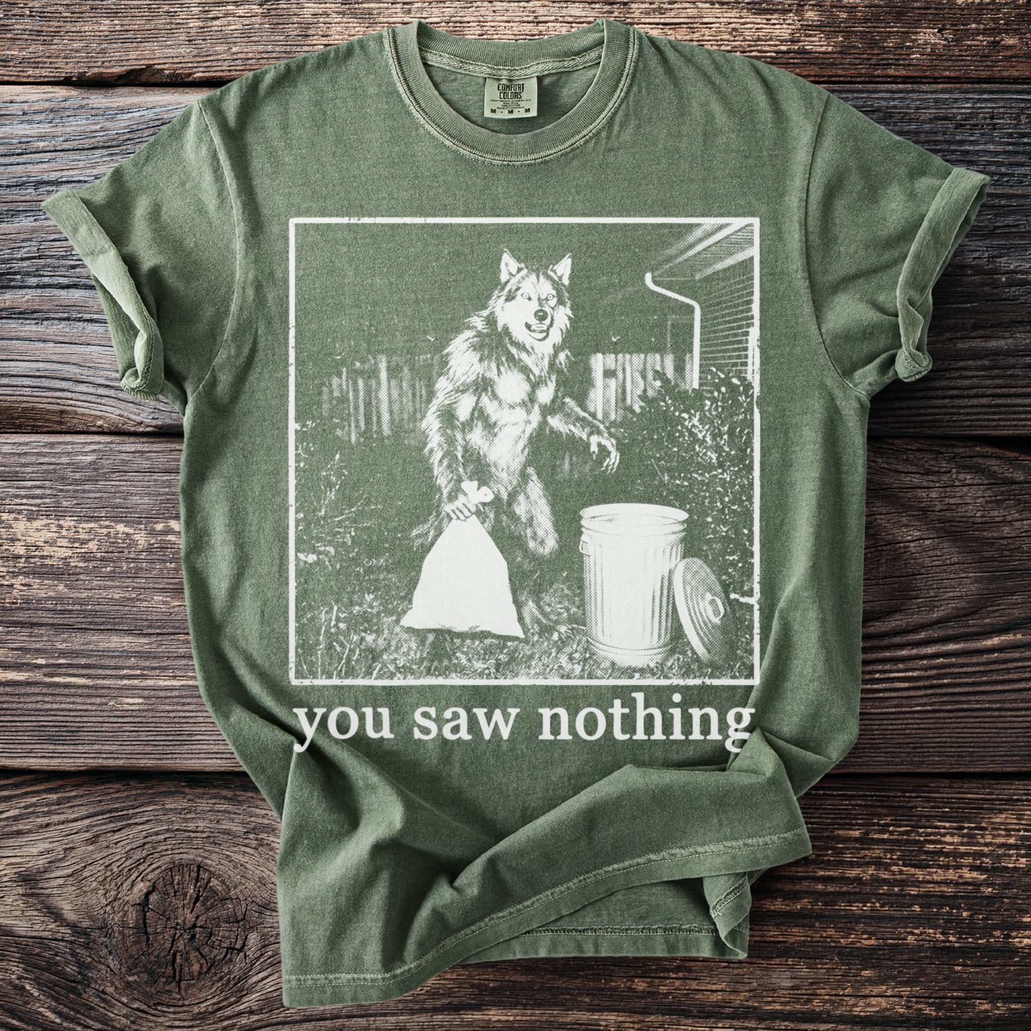 Green t-shirt with graphic of a werewolf taking out trash and text "you saw nothing."