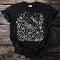 Black t-shirt with line art of dragonflies, moon, stars, and dandelions.